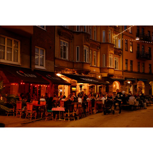 Menschen sitzen abends im Freisitz eines Restaurants und genießen die gesperrte Straße