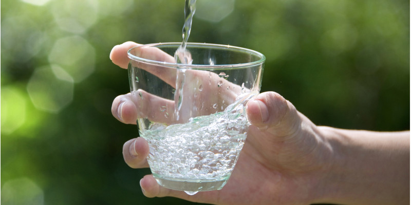 Eine Hand hält ein Glas Trinkwasser