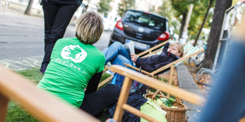 Menschen rasten auf Parkplatz an Straßenrand mit Sonnenliegen