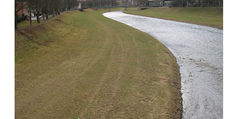 Foto: Ein Abschnitt der Murg vor der Renaturierung. Die Ufer des Flusses sind bis auf kurz gehaltenes Gras völlig frei von Vegetation. Das Gewässer selbst ist sehr monoton, ohne Inseln, Kiesbänke oder andere Strukturen.