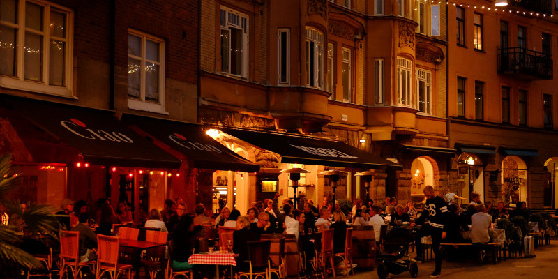 Menschen sitzen abends im Freisitz eines Restaurants und genießen die gesperrte Straße