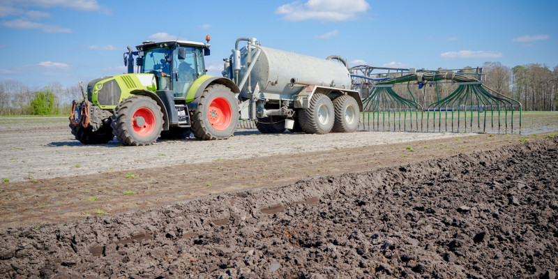 Foto: Ackerfläche mit Traktor und Schleppschlauchapplikator.