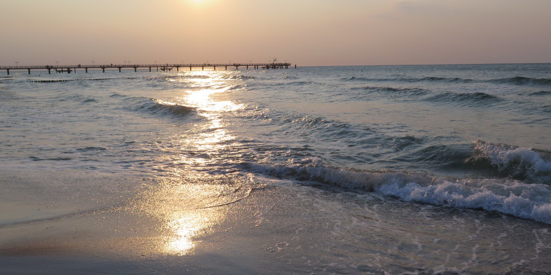 Sandstrand mit Brücke im Hintergrund. 