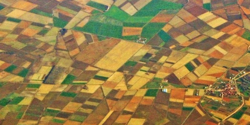 Bird's eye view of geometrical arranged, colourful fields and settlements