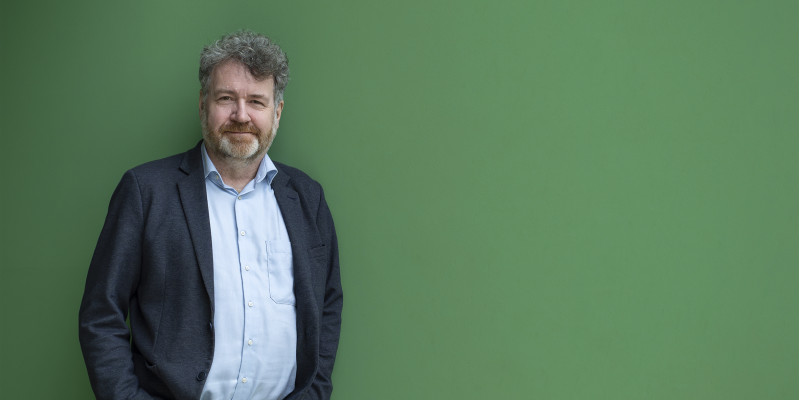 Dr. Erik Schmolz vor einem grünen Hintergrund