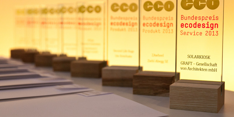 Trophies with the logo of the Bundespreis Ecodesign an the names of the winners standing on a table