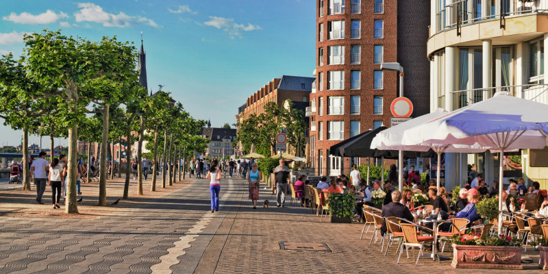 Fußgängerzone in der Stadt, in der Menschen spazierengehen, joggen oder draußen in Cafés sitzen