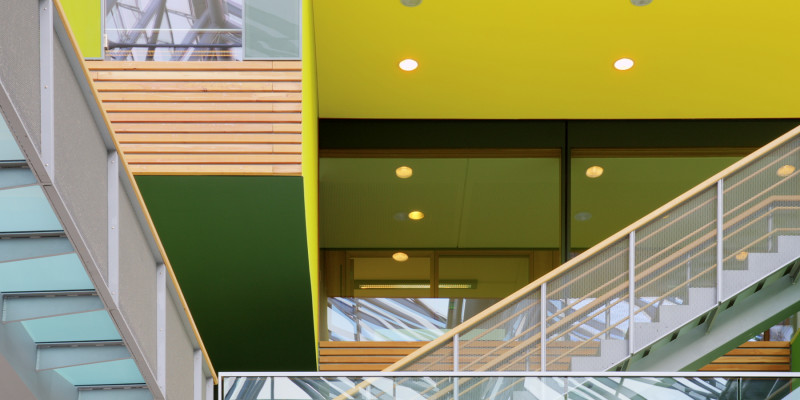 Skywalks and stairs with glass banisters in inner courtyard, inner façade of wood, yellow and green surfaces