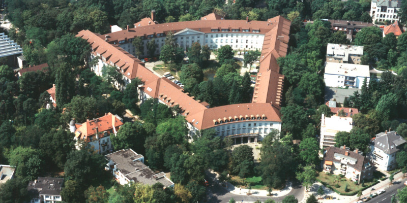 Triangular building complex with green inner courtyard nestled in an urban district with many trees