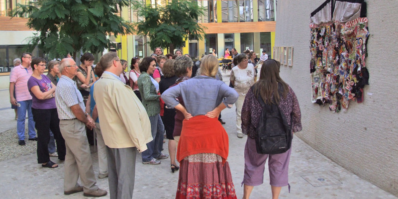 Besucher der Kunstausstellung stehen vor einem geknüpften Wandteppich, der im Atrium des UBA in Dessau hängt