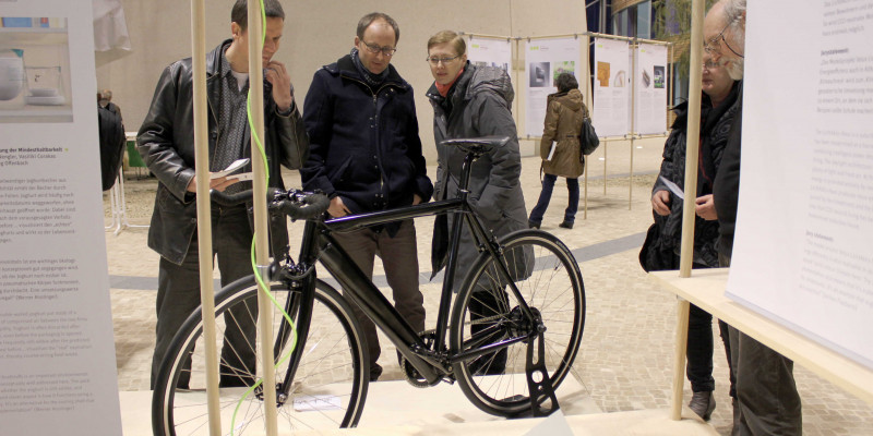 Besucher der Wanderausstellung sehen sich das ausgestellte Elektrofahrrad im Atrium im UBA Dessau an.