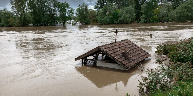 Bild zeigt eine überschwemmte Landfläche, auf welcher ein Schuppen stand; dieses ist jedoch überflutet