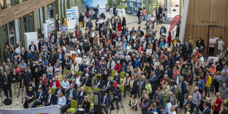 Ein Foto aus der Vogelperspektive vom Jubiläumsfest am 15.06.2024 in Dessau-Roßlau mit vielen Gästen, die im Forum des Umweltbundesamtes stehen. 