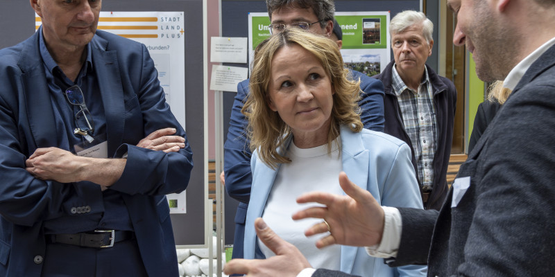 Dirk Messner und Steffi Lemke vor einem Computer mit einem Kollegen des KI-Labs 