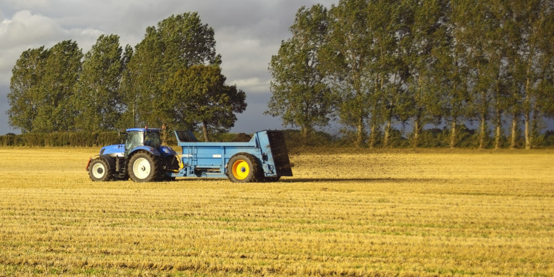 A tractor spreading fertilizer on a field 