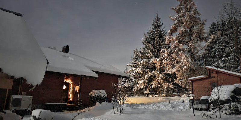 Eine Wärmepumpe vor Holzhaus im Schnee.