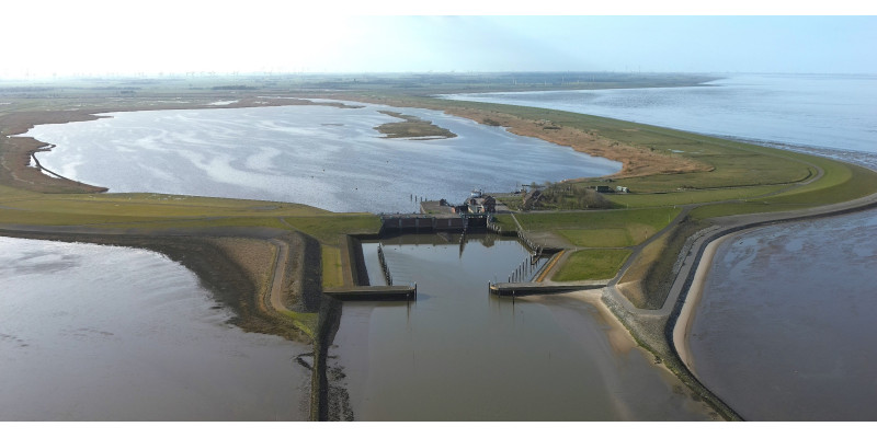 Das Bild gibt mit Blick von oben das Sperrwerk Leysiel und Speicherbecken Leyhörn wieder. Es wird wie eine von außen und innen mit Wasser umgebenes Eiland.