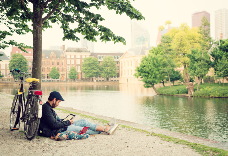 Ein sitzt an einem Fluss, lehnt an einem Buch und liest ein Buch.