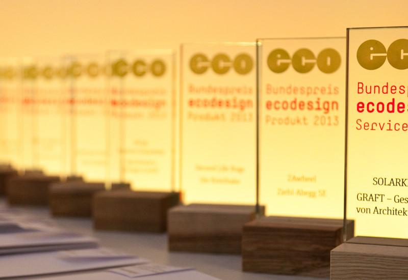 Trophies with the logo of the Bundespreis Ecodesign an the names of the winners standing on a table