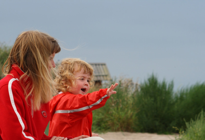 Mutter und Tochter an der See auf einer Düne sitzend