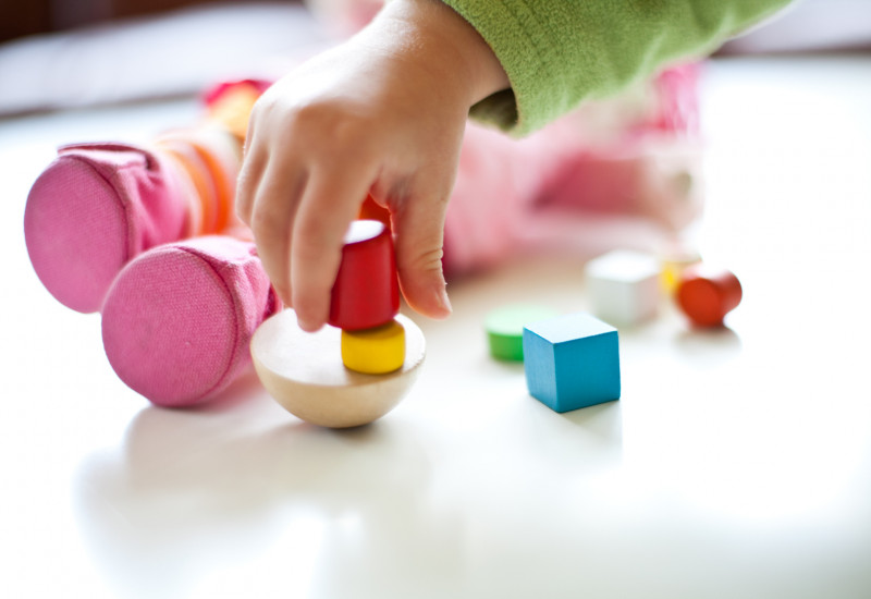 Nahaufnahme einer Kinderhand, die mit Bauklötzen spielt