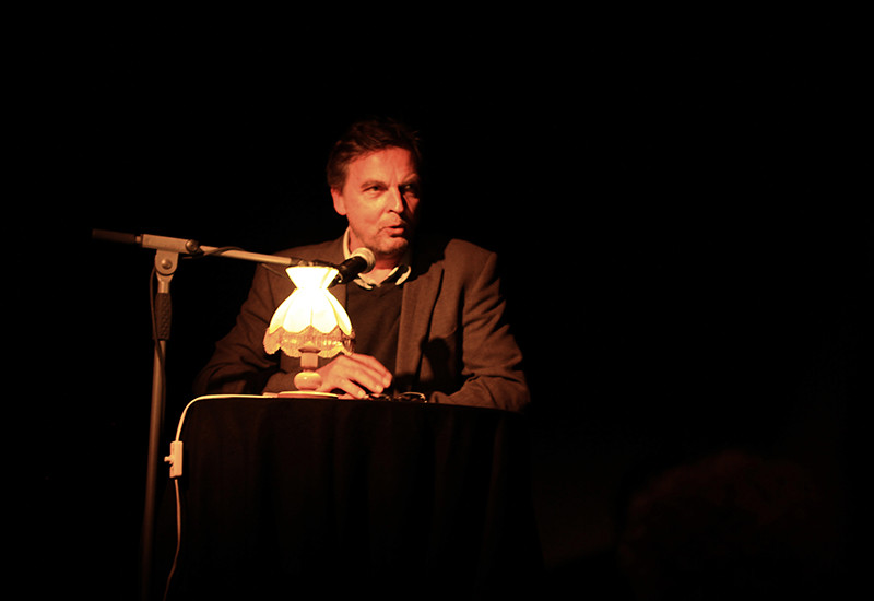 Ein Mann liest auf einer Bühne aus einem Buch