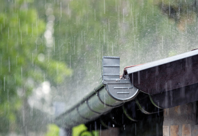 Das Bild zeigt die Regenrinne eines Hauses as Klinkermauerwerk. Es regnet stark.