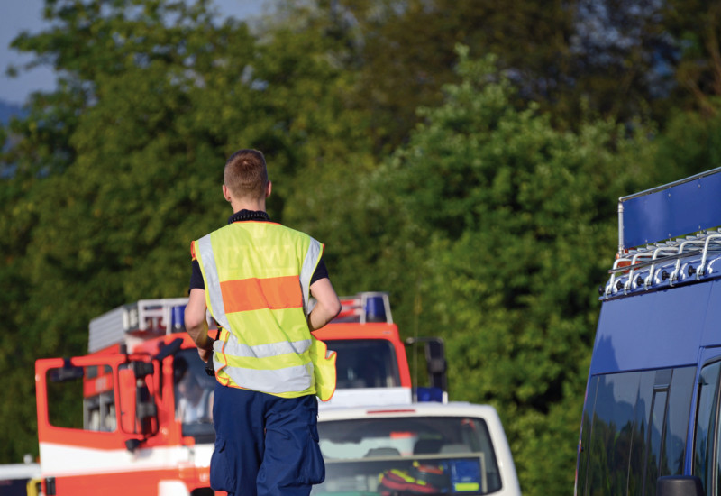 Das Bild zeigt drei Einsatzfahrzeuge der Feuerwehr und des Technischen Hilfswerks, die auf einer Überlandstraße stehen, darunter ein Löschgruppenfahrzeug. Ein Mann mit Warnweste und Einsatzhose des THW läuft auf der Mittelleitplanke.