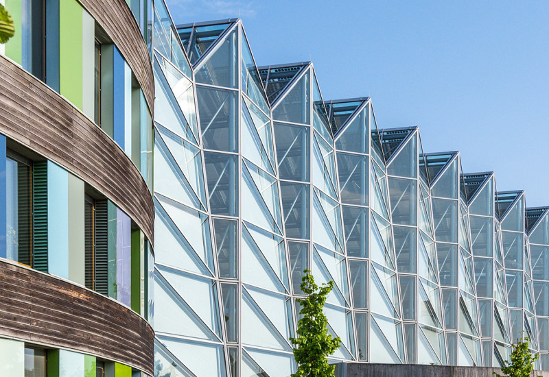 Zu sehen ist das Hauptgeäude des Umweltbundesamtes in Dessau-Roßlau. Im Anschtt befindet sich ein Teil der bunten Fassade sowie die Blickrichtiung zum gläsernen Haupteingang. 