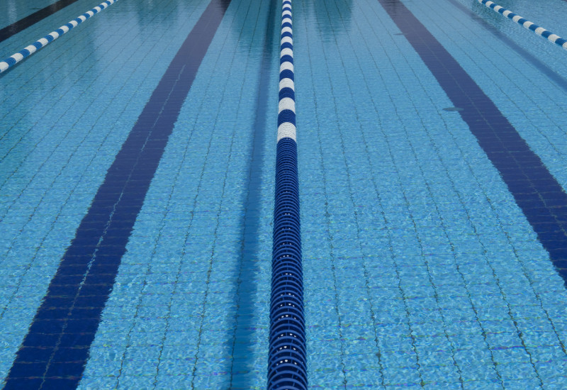 Das Wasserbecken eines Schwimmbades, wo die Bahnen durch schwimmende Abgrenzungen voneinander abgetrennt sind. Nahaufnahme