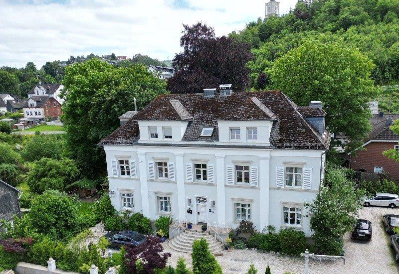 Eine Luftaufnahme einer denkmalgeschützten Villa mit zwei Geschossen.