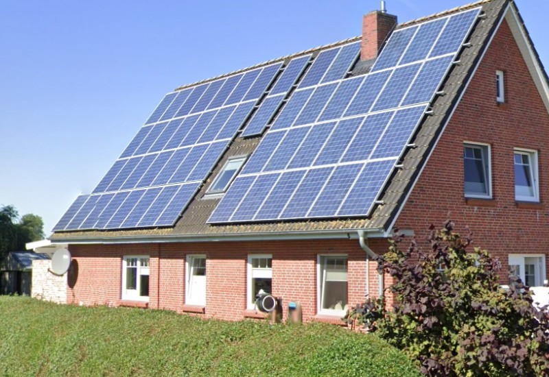 Ein geklinkertes Haus mit Photovoltaik auf dem Dach.