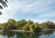 The picture shows the oxbow lake of a river with unfortified banks lined with meadows and tree clusters.