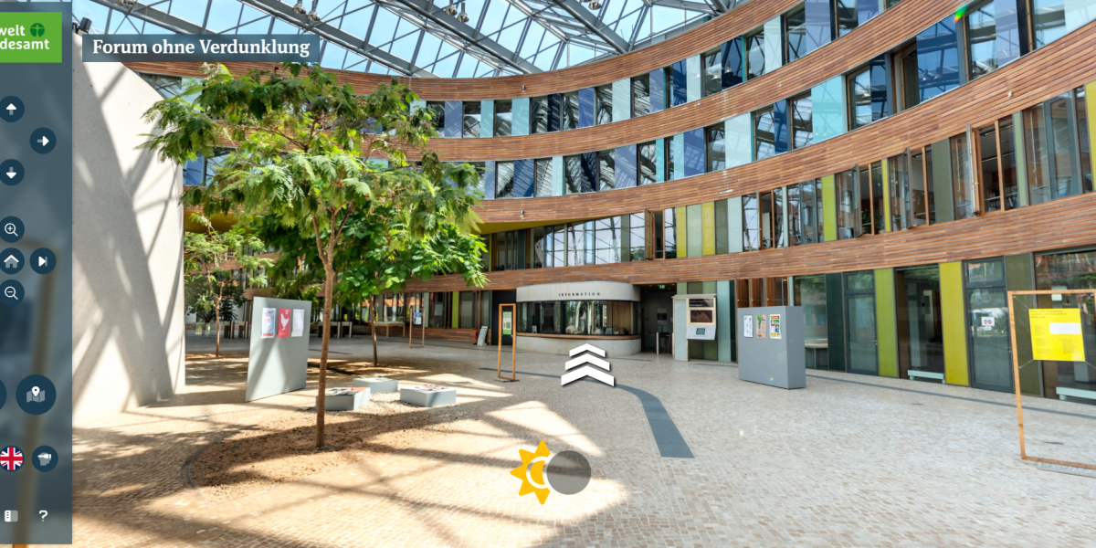 Screenshot aus dem virtuellen Rundgang durch das UBA-Gebäude Dessau, ein modernes Bürogebäude mit viel Glas, Holz, farbig gestalteten Flächen und einem bepflanzten Atrium